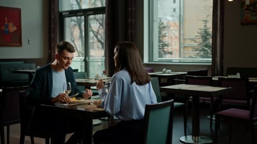 Date in the hotel restaurant dinner man and woman drink white wine in glasses and taste food
