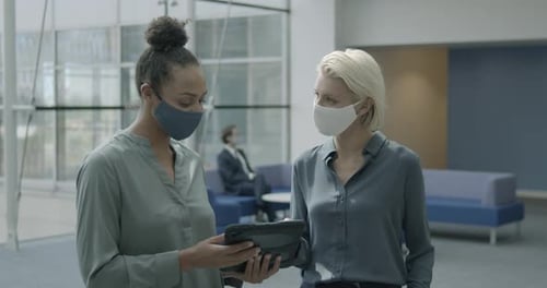 Business people office meeting in lobby wearing protective face mask and using digital tablet