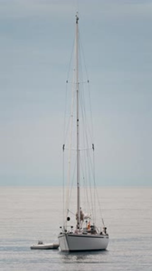 Distant view of a white boat floating on the Mediterranean Sea in daylight. Vertical