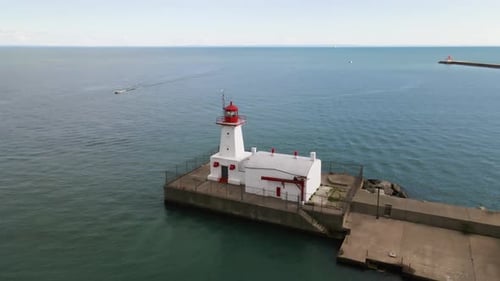 Luftaufnahme eines historischen weißen Leuchtturms, der über tiefblauem Wasser steht