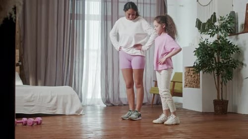 Woman and Girl Exercising Together in Bedroom