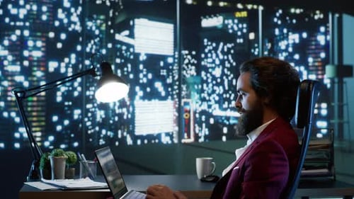 Man Working At Desk With City View At Night