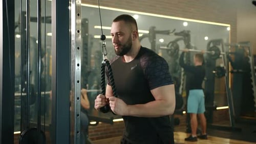 Slow Motion Medium Shot of Athletic Young Man Training on Vertical Row Machine