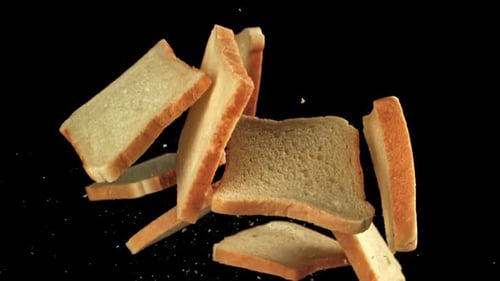 Trozos de pan fresco vuelan sobre un fondo negro filmados con una cámara de alta velocidad a 1000 fps