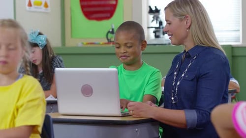 Teacher And Student Use Laptop Computer In School Classroom
