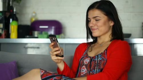 Woman Relaxing on Sofa Using Mobile Phone