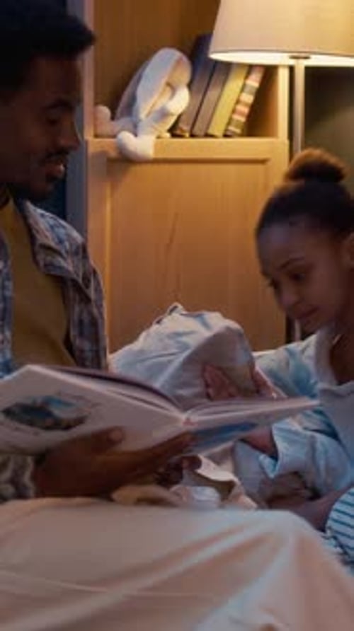 Man Reads Bedtime Story to Child in Bedroom