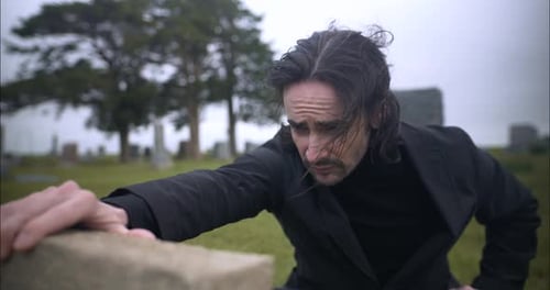 Man in Black Mourning at Cemetery Headstone