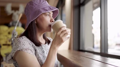 Woman Drinking Coffee by the Window in Cafe