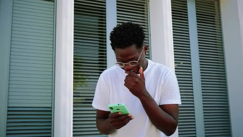 Young Man Smiling Using Phone Outdoors
