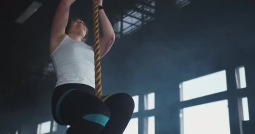 Beautiful Young Muscular Athletic Blonde Woman Climbs Rope at Gym Jumps Down Breathing Heavy and