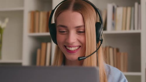 Smiling Woman Wearing Headset using Laptop