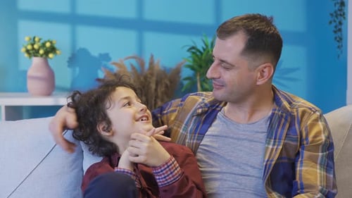 Man and Boy Talking on Couch Together