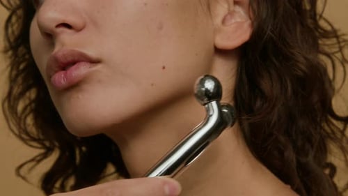 Nahaufnahme einer jungen Frau, die mit einer Heberolle vom Kinn bis zum Ohr massiert
