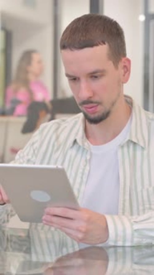 Man Using a Tablet Device Indoors During the Day
