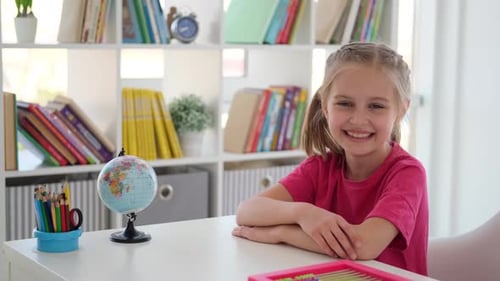 Smiling Little Girl Sitting at School Desk