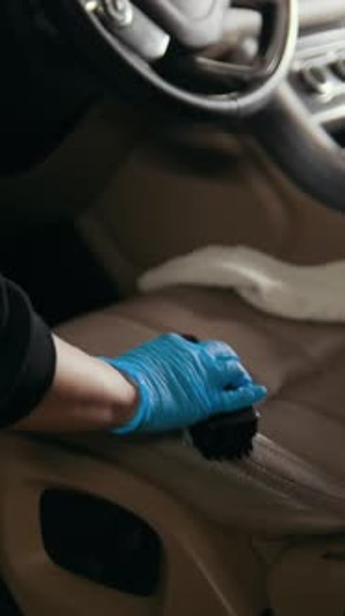 Detailer Cleaning Car Seat Interior with Brush
