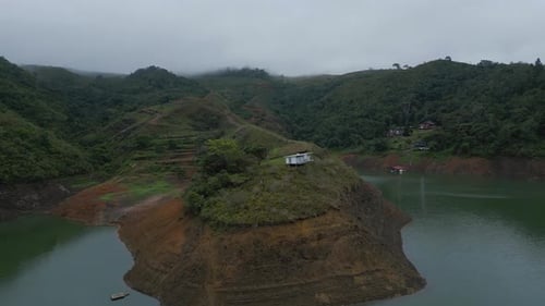 Aerial Flying Over Hill with Small House on Top in Lake Calima