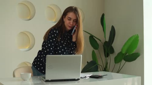 Young Businesswoman a Woman Working in an Office Standing at a Desktop with a Laptop Holding