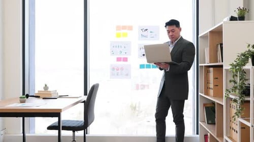 Asian Businessman Engaging in Virtual Meeting with Charts and Graphs