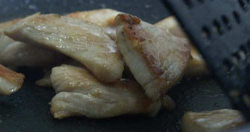 Chicken Pieces Cooking on Griddle with Spatula