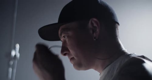 Man Putting in Earbuds in Dark Room