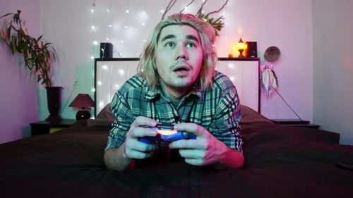 Young Man Playing Video Game in Bedroom at Night