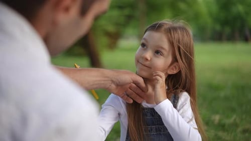 A Child Covers Their Ears in a Park with an Adult Nearby Evoking Rich Emotion and Exploration