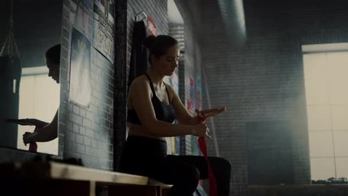 Athletic Woman Wraps Hands in Gym for Boxing
