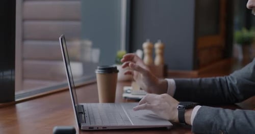 Slow Motion Tiltup Portrait of Businessman Working with Laptop and Drinking Coffee at Table in Cafe