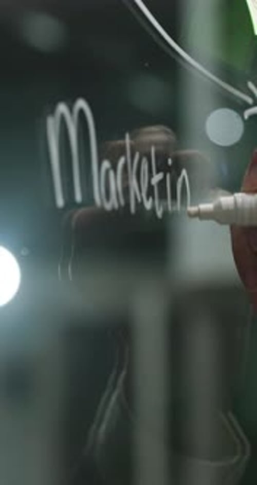 Writing Marketing Strategy on Glass Whiteboard Close Up