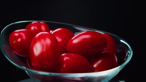 Cherry Tomatoes in a Glass Transparent Bowl are Grown on a Black Background