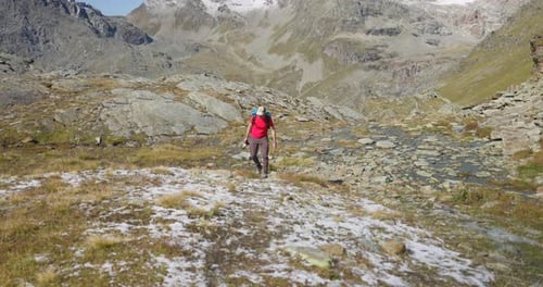 Photographer walks through autumn mountain landscape with the first snow