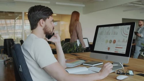 Businessman Discussing Financial Report on Phone at Office Workplace