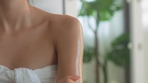 Woman Applying Lotion on Arm Wrapped in Towel
