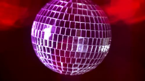 Spinning Disco Ball Reflects Red and Pink Lights
