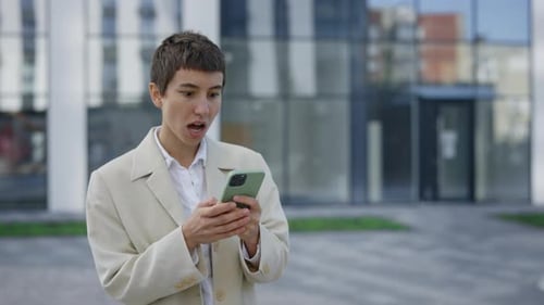 Young Adult Celebrates Success Using Mobile Phone