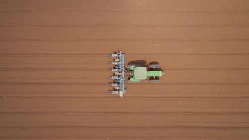 Green tractor cultivating a field - Aerial footage