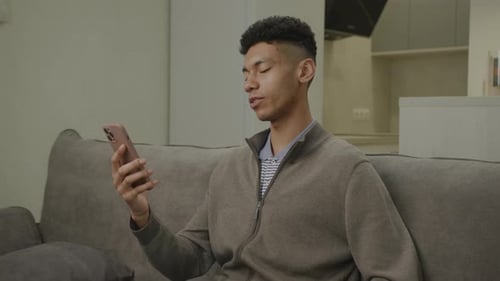 Young Adult Video Calling on Smartphone from Couch