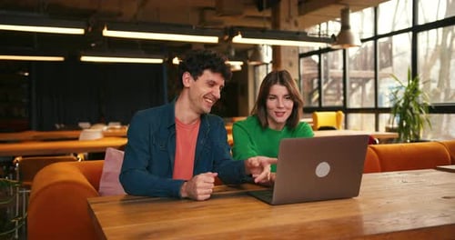 Colleagues Brainstorming New Ideas Using Laptop in Modern Cafe