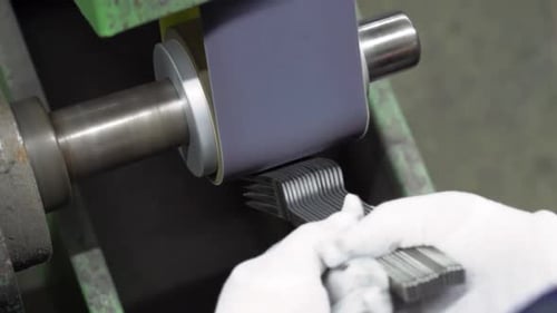 Handaufnahme in Zeitlupe eines Arbeiters, der eine Reihe von Gabeln mit industriellem Einschlag schleift und poliert