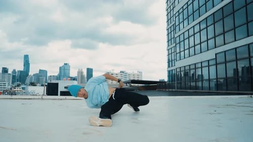 Stylish caucasian dancing man performing break dance at skyscraper. hiphop.