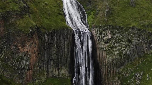 Aerial View of Stunning Mountain Waterfall in the Middle of Green Alpine Meadows