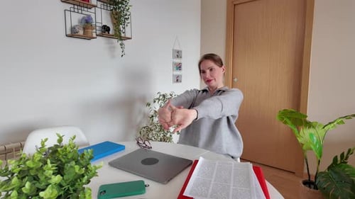 Woman Stretching and Reading at Home Office Desk