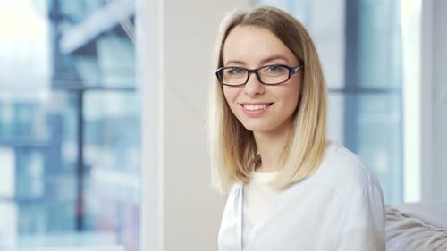 Close-up portrait a caucasian young blonde woman indoors looking at camera and smiling. Cute Happy