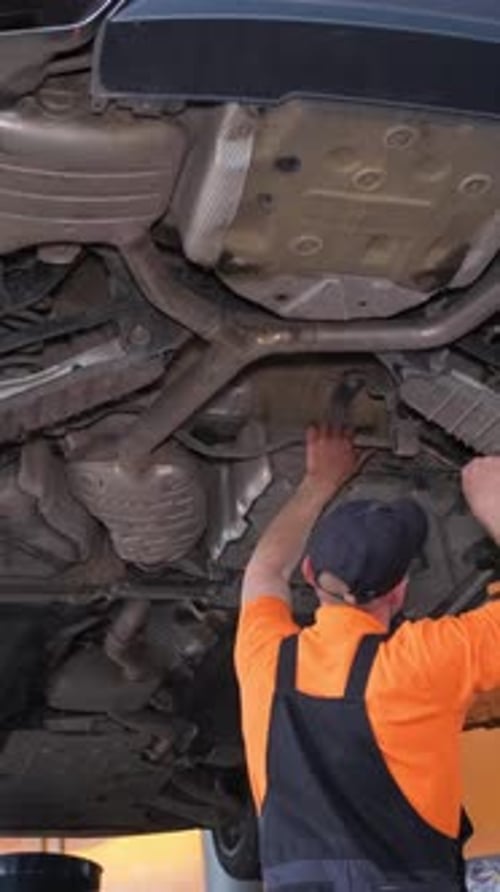 Man Working Under Car on Lift in Garage for Automotive Tire Event Vertical Video