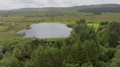 Aerial View Of Calm Lake Surrounded By Lush Green Forest And Mountains