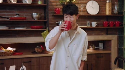Young Man Enjoys Drink in Sunny Kitchen
