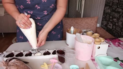 Eine Frau gießt Eiscrememischung in eine mit Schokolade bestrichene Silikonform.