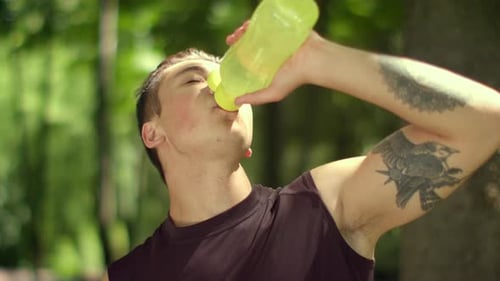 Athletic Man Drinks Water From Bottle Outdoors